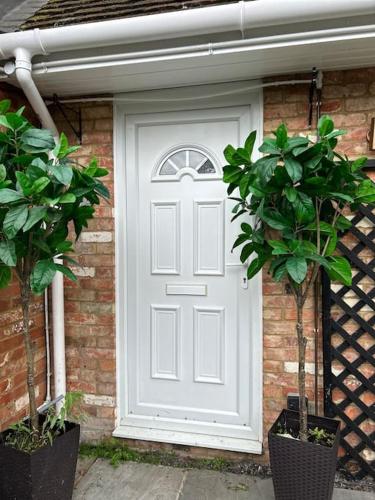 a white door on a brick house with two plants at Meadow view in Hurst
