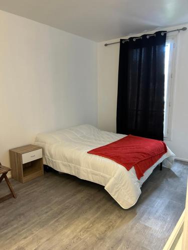 une chambre avec un lit avec une couverture rouge et une fenêtre dans l'établissement Studio très lumineux et équipée en pleine avenue !, au Kremlin-Bicêtre