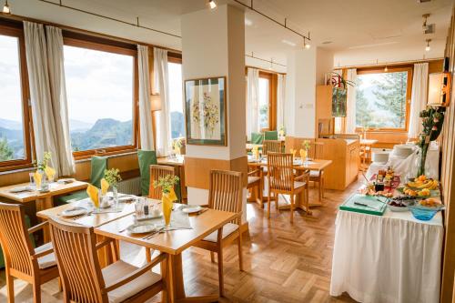a restaurant with wooden tables and chairs and windows at Panoramahotel Wagner - Das Biohotel am Semmering in Semmering