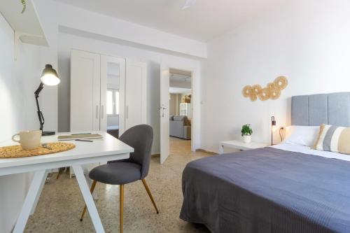 a white bedroom with a bed and a desk at Apartamento en el Paseo de Oliva in Oliva