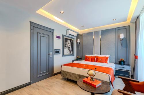 a bedroom with a bed with orange pillows and a table at Atar Airport Hotel - Spa & Wellness in Arnavutköy