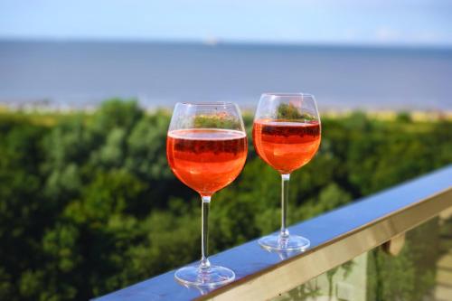 two glasses of wine sitting on top of a railing at Panoramameerblicksuite direkt am Strand, Garage Wlan, Aufzug, Smarttv,Bettwäsche,Handtücher, Netflix uvm in Cuxhaven