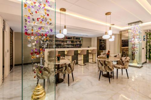 a dining room with tables and chairs and a glass wall at Atar Airport Hotel - Spa & Wellness in Arnavutköy