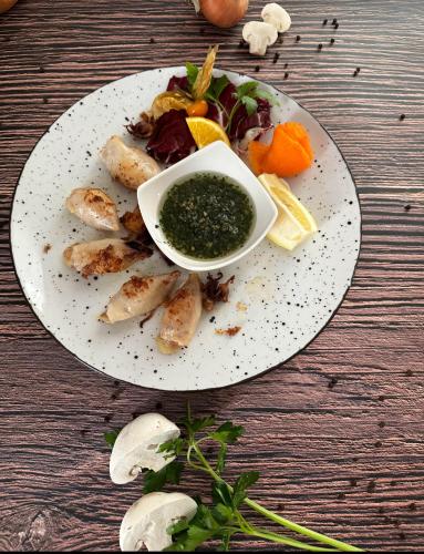 a plate of food with a bowl of green sauce at Guesthouse Pri Tonetu in Ptuj