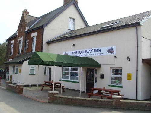 un edificio con dos mesas de picnic delante de él en Railway Inn en Culham