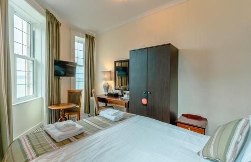 a bedroom with a bed and a desk and a chair at Gairloch Hotel 'A Bespoke Hotel' in Gairloch