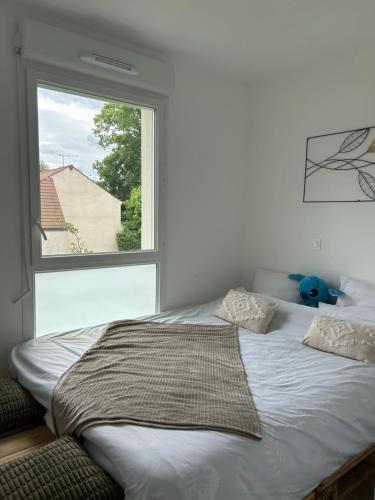 un lit dans une chambre avec une grande fenêtre dans l'établissement Appartement PARIS-Le Plessis-Trévise, à Le Plessis-Trévise