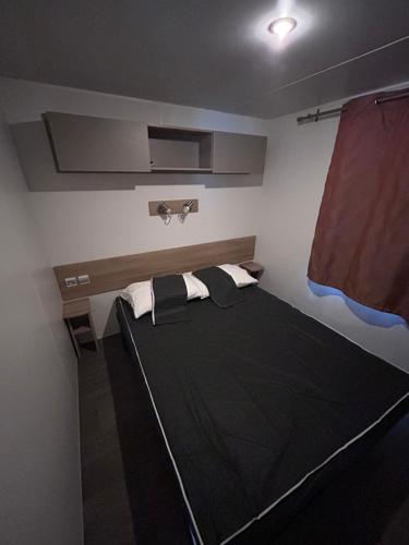 une chambre avec un lit noir dans une pièce dans l'établissement Mobil Home 2 chambres, 4 à 6 personnes, Vias Plage, Camping La Carabasse - 4 étoiles, à Vias