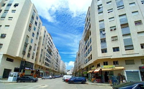 a street with two tall buildings and parked cars at EXCELLENT rapport Qualité Prix pour cet Appartement 3 étoiles 2P Tout Confort Clim Reversible Résidence Golf Mesnana Tanger in Tangier