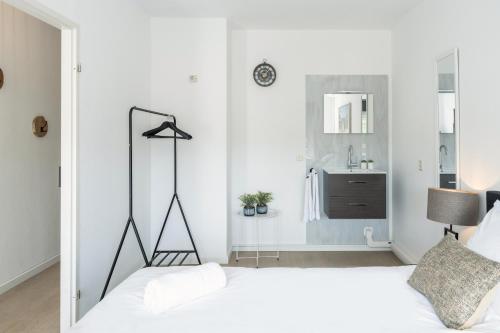 a white bedroom with a bed and a mirror at Prime Location Apt W Wifi & Near Poppodium 013 in Tilburg