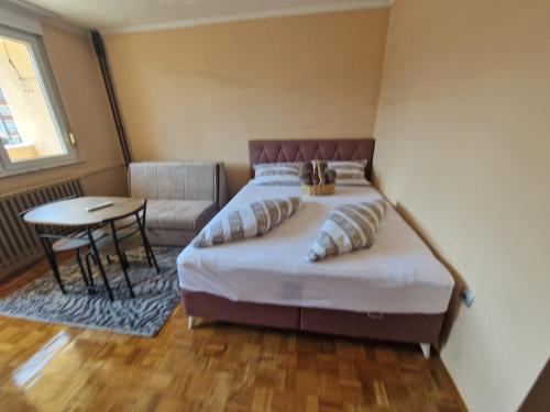 a bedroom with a bed and a table and a chair at Cozy in Zenica