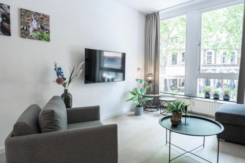 a living room with a couch and a tv on a wall at Prime Location apt w wifi & near poppodium 013 in Tilburg