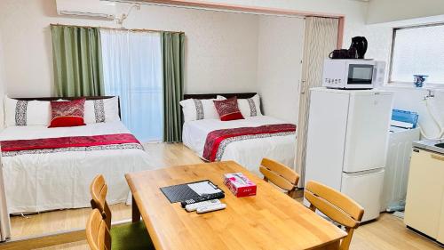 a small room with two beds and a table at ゲストハウスROOASiS常磐町301 in Takamatsu