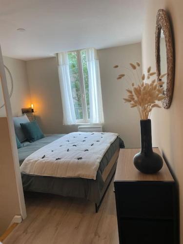 - une chambre avec un lit et un vase sur une table dans l'établissement Chez BA&PA, à LʼIsle-sur-la-Sorgue