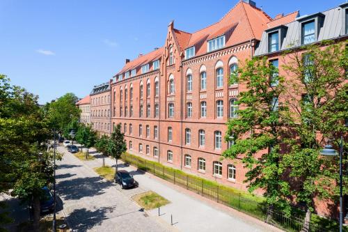 a large red brick building on a street at ARCHE Dwór Uphagena Gdańsk in Gdańsk