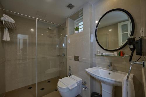 a bathroom with a toilet and a sink and a mirror at The Old Court House By Abad in Cochin
