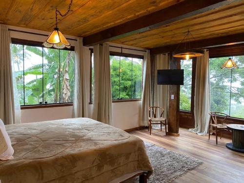 ラブラス・ノーヴァスにあるChalé da Mata Lavras Novasの窓のある部屋にある大きなベッドのある寝室