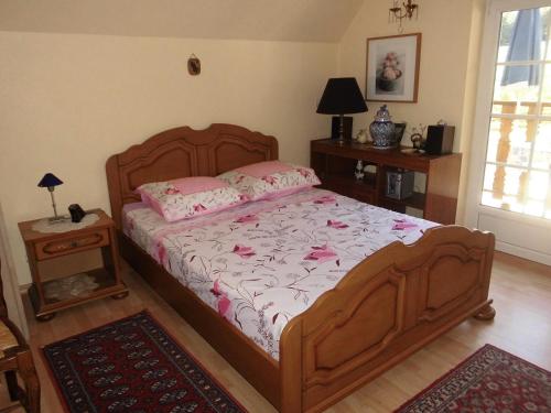 a bedroom with a wooden bed with pink flowers on it at Aux Vignes in Rott