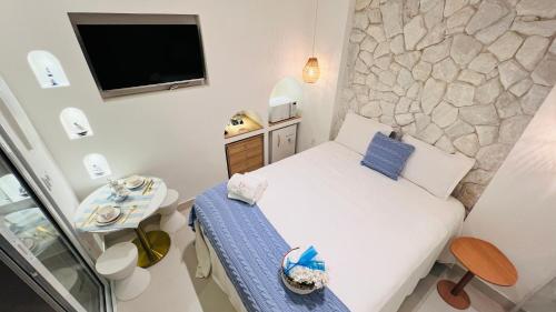 a small bedroom with a bed and a tv at D'Blue Búzios Hotel Boutique in Búzios