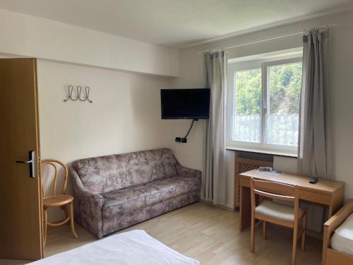 a living room with a couch and a desk and a television at Gasthof Majestic in Bressanone