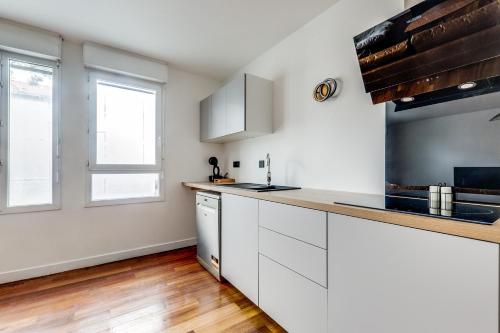 une cuisine avec des armoires blanches et un comptoir dans l'établissement Porte de Paris - Stade de France, à Saint-Denis