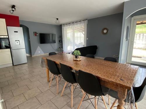 a dining room table with black chairs and a kitchen at Maison au calme avec terrasse in Saint-Julien-en-Saint-Alban