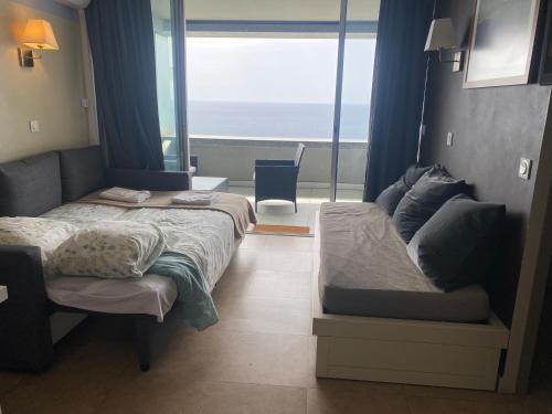 a bedroom with a bed and a couch and a window at Sunny Home Costa Plana-Monaco -Cap D'Ail in Cap d'Ail