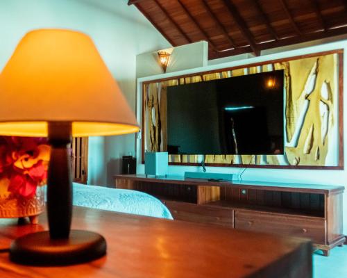 a bedroom with a television and a lamp on a table at Hotel de Charme Illuminare Stile in Fortim