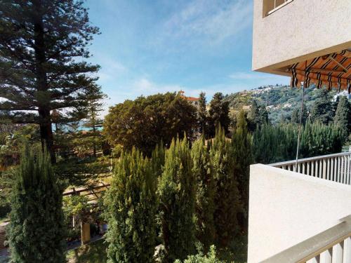 - un balcon d'une maison avec des arbres et une montagne dans l'établissement Appartement Calme avec Terrasse et Parking à 5 min de la Mer à Menton - FR-1-196-203, à Menton
