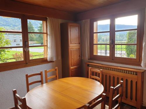 une salle à manger avec une table en bois et trois fenêtres dans l'établissement Appartement calme près du lac avec jardin, terrasse, parking et WiFi - FR-1-624-45, à Samoëns