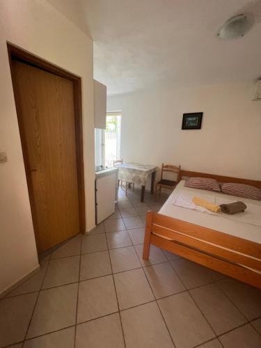 a bedroom with a bed and a table and a door at Apartments Svekrić in Novalja