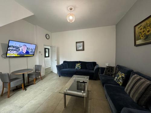 a living room with blue couches and a flat screen tv at 4 BR, Large & Modern Private House Central Location in Newcastle upon Tyne