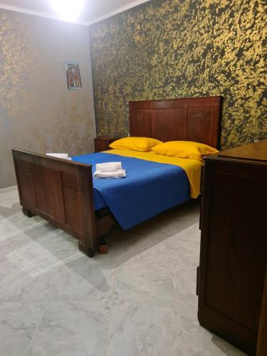 a bedroom with a bed with blue sheets and yellow pillows at Cilento House Garden B&B MIRELLA in Poderia