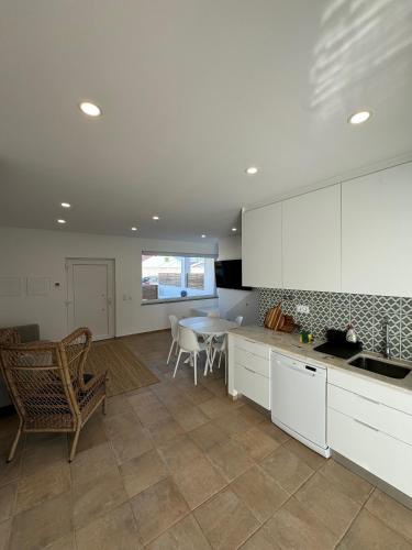 a kitchen with white cabinets and a table and chairs at TALAFA Beach House - Almograve in Almograve
