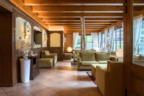 a living room with couches and tables and windows at Hotel Betulla in Madonna di Campiglio