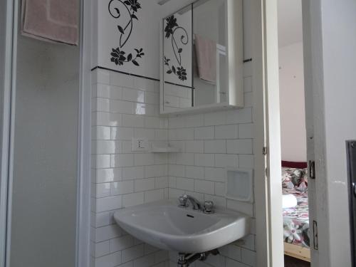 a white bathroom with a sink and a mirror at Suite Romeo-monolocale intimo vicino alle spiagge in Grado