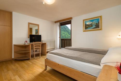 a bedroom with a bed and a desk and a window at Hotel Betulla in Madonna di Campiglio