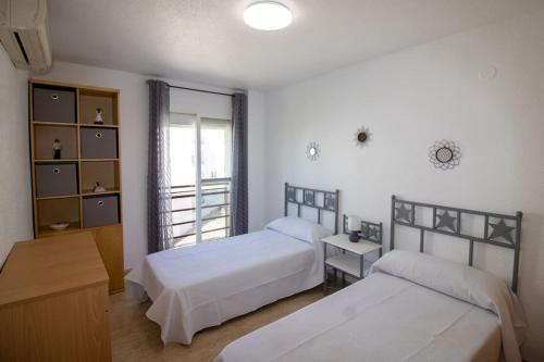 a bedroom with two beds and a table and a window at Apartamento superior - Alcocebre in Alcossebre