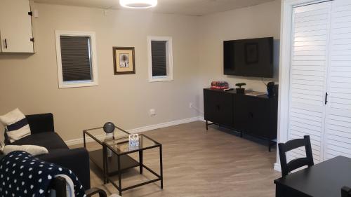 a living room with a couch and a flat screen tv at Cozy home on a quiet street minutes to DT Kingston in Kingston