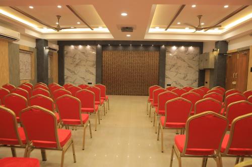 a conference room with red chairs and a screen at KANS ONE - Hotel & Banquets in Chennai