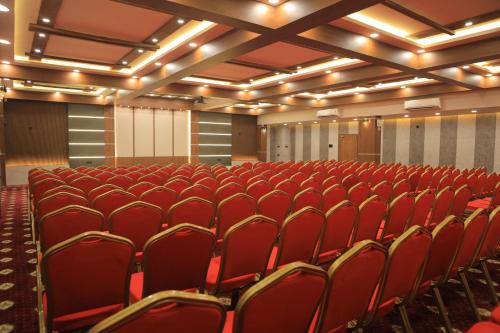an empty auditorium with red chairs in a room at KANS ONE - Hotel & Banquets in Chennai