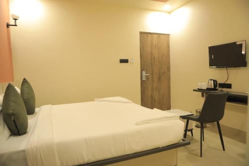 a bedroom with a bed and a chair and a television at KANS ONE - Hotel & Banquets in Chennai
