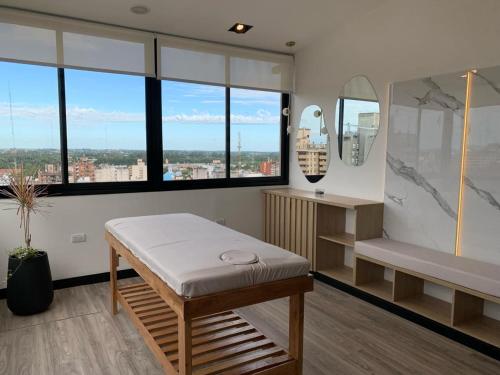 a room with a bed and a bench and windows at Garden Plaza in San Miguel de Tucumán