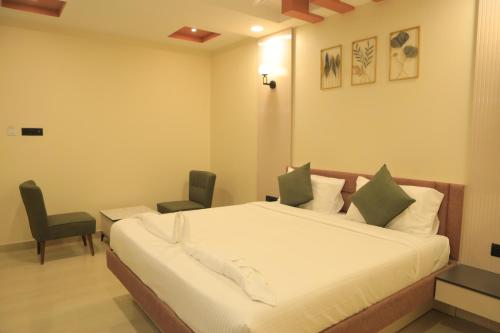 a bedroom with a large bed and two chairs at KANS ONE - Hotel & Banquets in Chennai