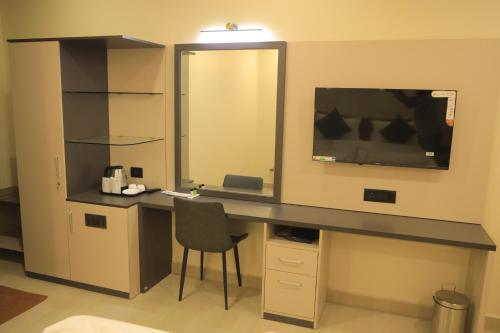 a desk with a mirror and a chair in a room at KANS ONE - Hotel & Banquets in Chennai