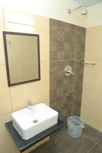 a bathroom with a sink and a mirror and a shower at KANS ONE - Hotel & Banquets in Chennai