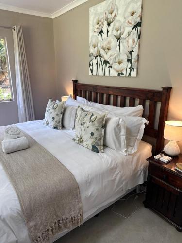 a bedroom with a bed with white sheets and pillows at Eagles Rest Cottage in Greytown