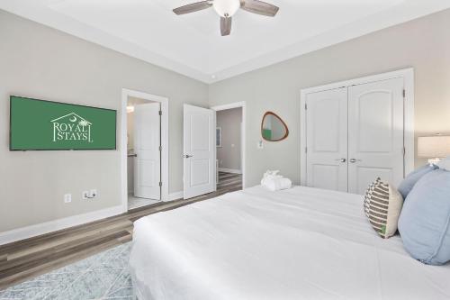 a white bedroom with a bed and a tv on the wall at Pier View - Spacious Home Sleeps 8 - Pet Friendly in Myrtle Beach