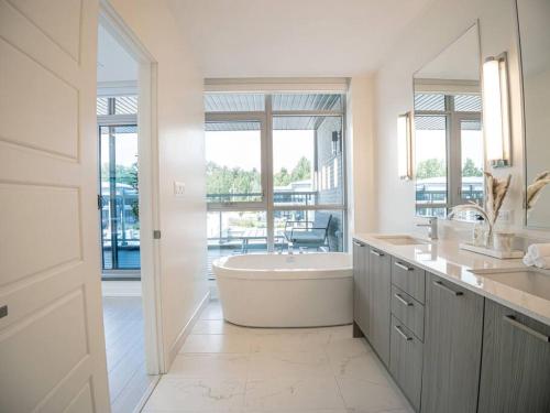 a white bathroom with a tub and a large window at Casa Lago 5 Bed Waterfront House in Innisfil