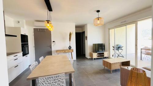 une cuisine et un salon avec une table et des chaises dans l'établissement Appartement MARINA 2 LUMIO, à Lumio